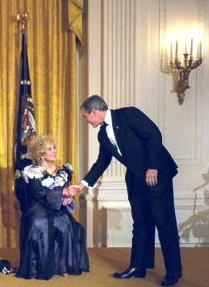 Liz Taylor shakes hands with President George W. Bush in the White House East Room, December 8, 2002. (Getty)