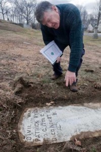 Historian Phil Gallagher examins Patrick Ryan's gravesite at St. Peter Cemetery in Danbury where Irish immigrants were buried. (Danbury Legal-Times)