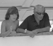 John Kennedy, Jr. and his stepfather looking over the yacht railing together.