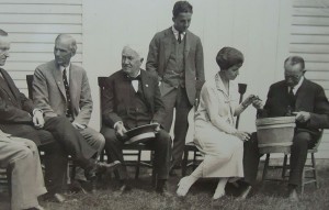 Grace Coolidge shows a sap bucket to her father-in-law which was autographed by Edison as well as Henry Ford - who speaks to President Coolidge at far left.