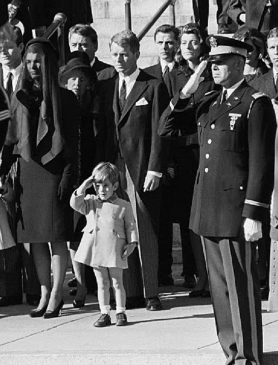 Following the President's funeral, Jackie stands as John salutes his father's casket, 1963, mimicking a military honor guard. Following the President's funeral, Jackie stands as John salutes his father's casket, 1963, mimicking a military honor guard.