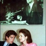 JFK's pictures hovers above his wife and son in 1989. (AP) JFK's pictures hovers above his wife and son in 1989. (AP)