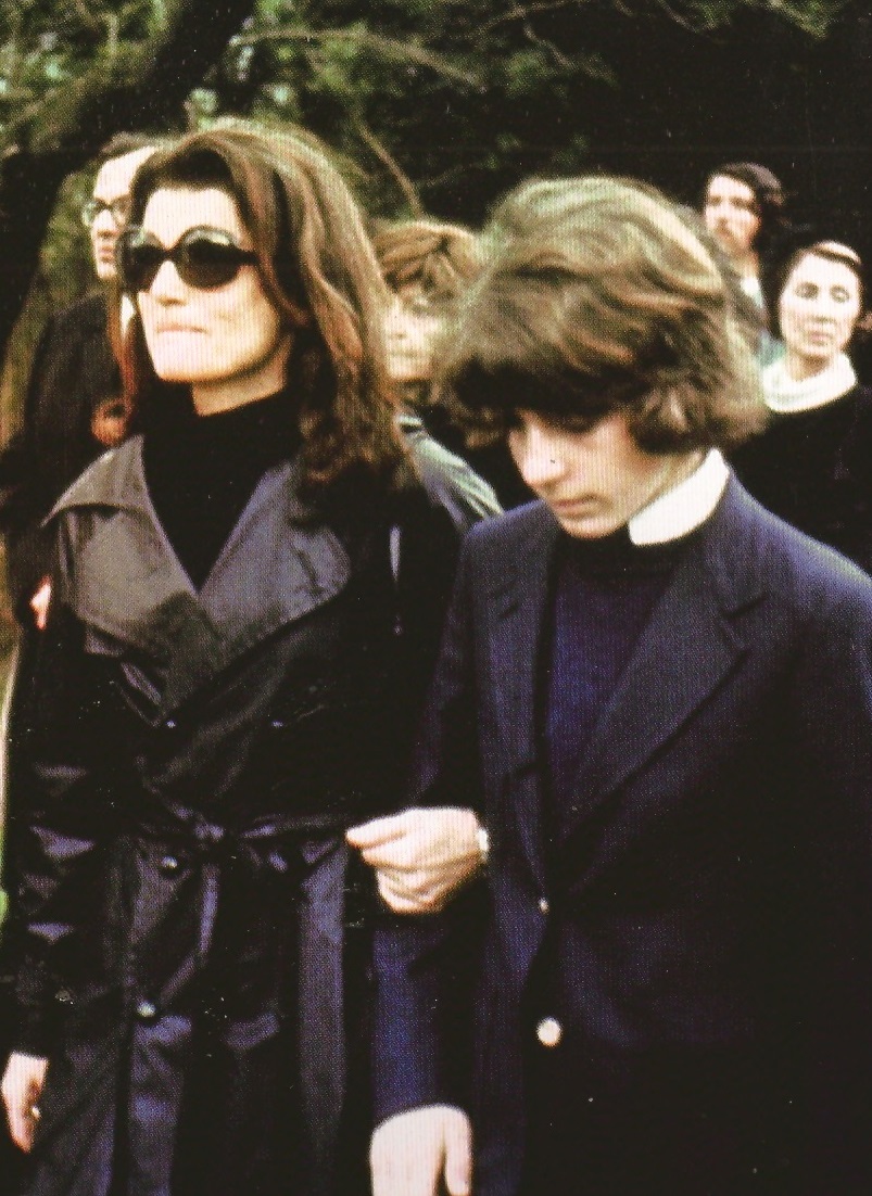 Jackie Kennedy Onassis took her son's arm as they proceeded towards the chapel funeral of her husband and his stepfather Ari. Jackie Kennedy Onassis took her son's arm as they proceeded towards the chapel funeral of her husband and his stepfather Ari.