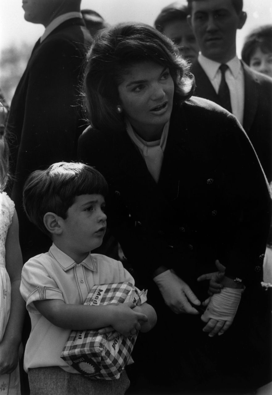 Jackie answers a question for her son while they were in England and he inexplicably clutches a loaf of bread, 1965. Jackie answers a question for her son while they were in England and he inexplicably clutches a loaf of bread, 1965.