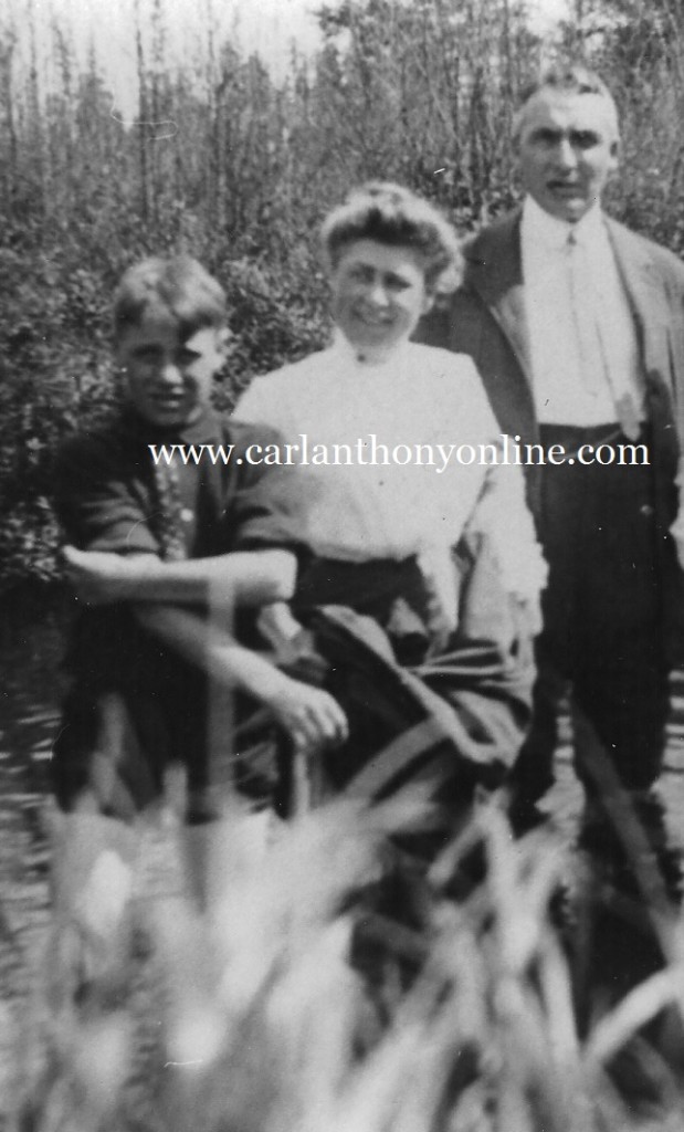 Warren and Florence Harding, and her son Marshall wading in a creek, skirt and trousers uplifted from the water.