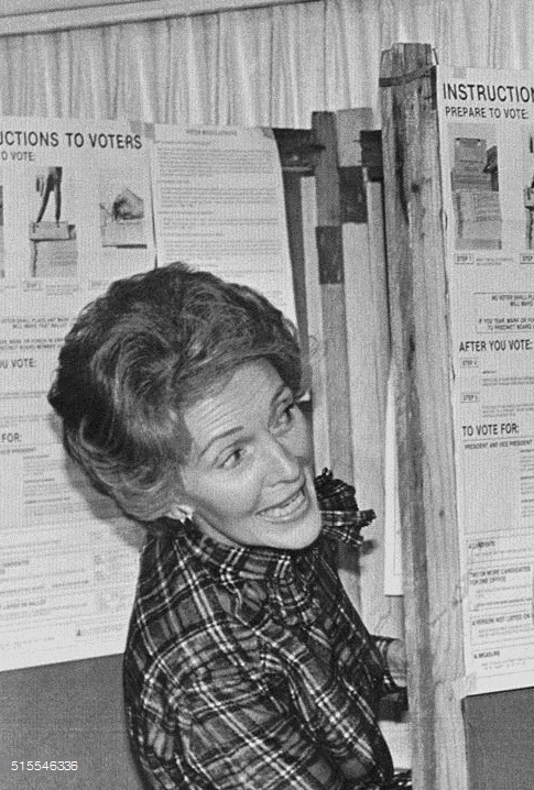 Nancy Reagan peeks over into her husband's voting booth as if to ask, "Hey, who'd you vote for?" in Pacific Palisades, California, 1980.