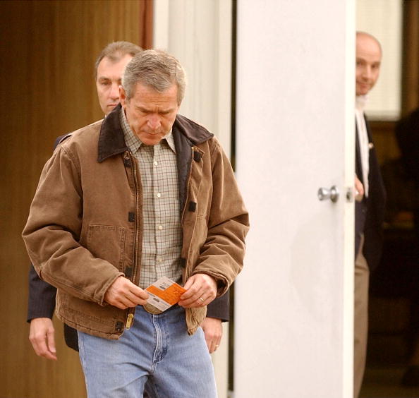 George W. Bush holds his voter registration card as he leaves a polling station at the Crawford Texas Fire Department, after casting his ballot for the mid-term elections during his first term as President. November 5, 2002. (Getty)