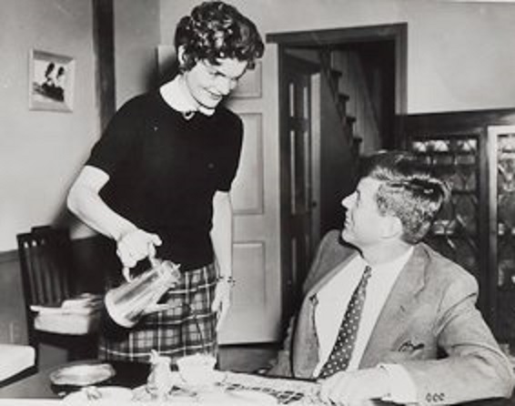 Striking a pose as the quintessentially submissive Fifties Housewife, Jackie Kennedy gets a smile from her husband as she pours his coffee.